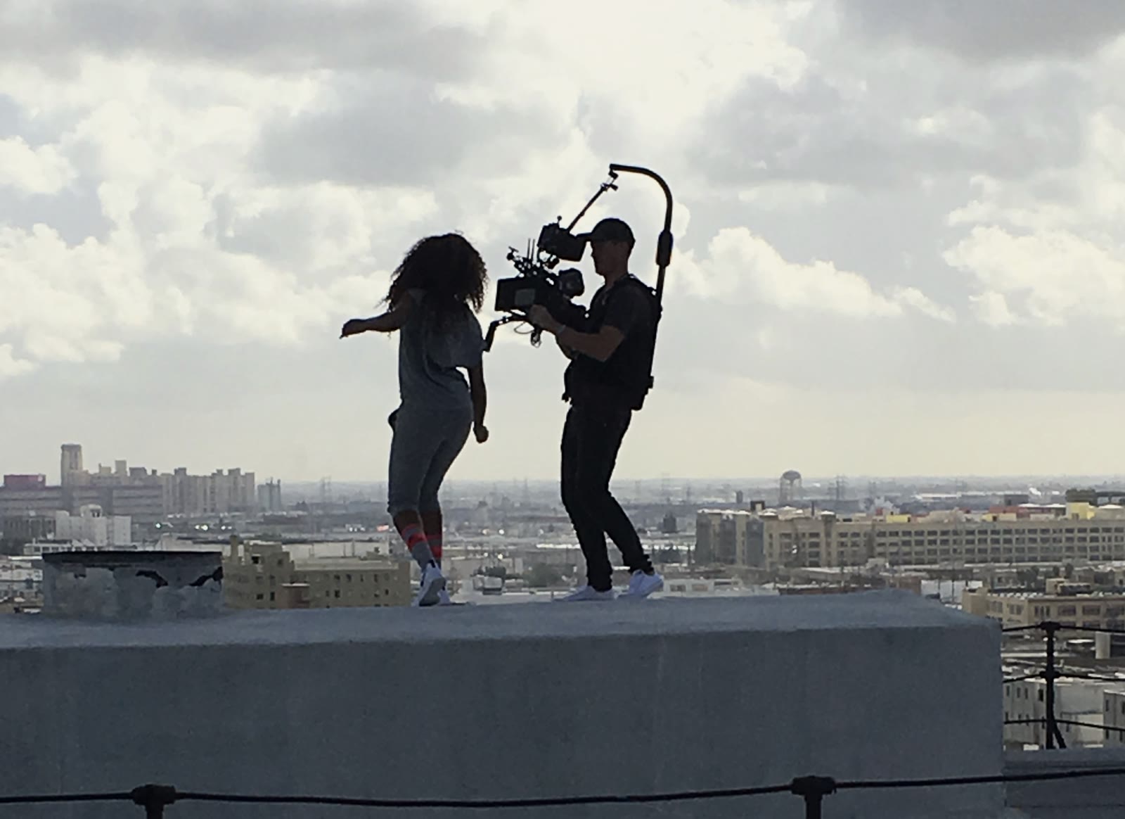 Paul Evans filming a dancer on a rooftop above the city